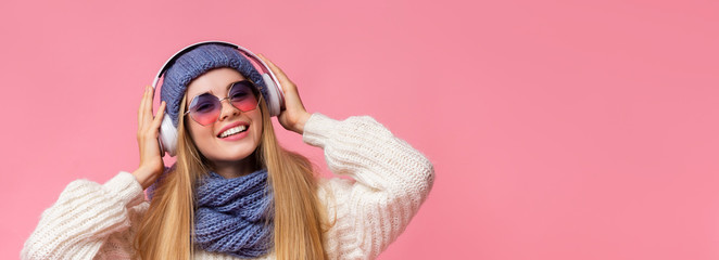 Cute winter girl enjoying music with modern wireless earphones