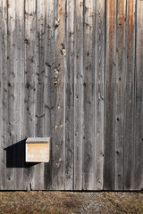 Dunkelgraue Holzwand mit gelbem Briefkasten