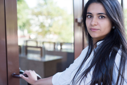 Portrait Of A Beautiful Young Indian Girl. Business Woman Opens The Door Of An Office Building, Going To Work