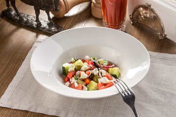 Fresh Greek salad in bowl with olives tomato feta cheese cucumber and onion on textile napkin