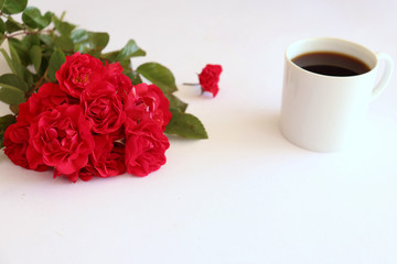 Hot coffe in awhite cup with natural red roses