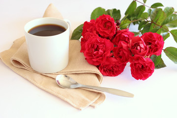 Hot coffe in awhite cup with natural red roses