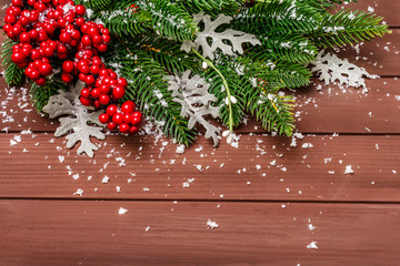 Christmas background. New Year fir tree, dog rose, fresh leaves and artificial snow. Wooden boards backdrop