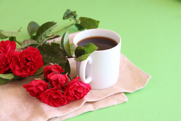 Hot coffe in awhite cup with natural red roses 