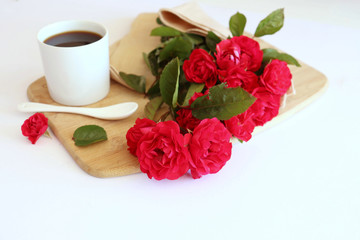 Hot coffe in awhite cup with natural red roses
