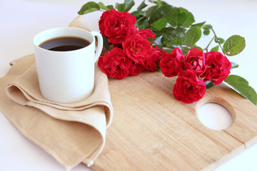 Hot coffe in awhite cup with natural red roses