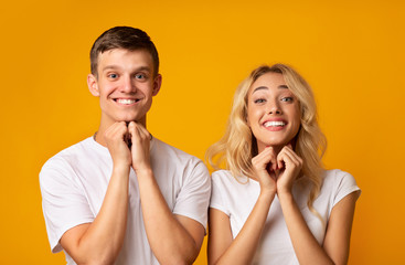 Young guy and girl pleading for something with clasped hands