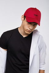 Cropped front view shot of a dark-haired man, wearing red baseball cap with lettering 