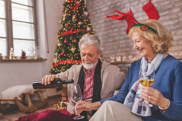 Senior couple drinking wine on Christmas day - Powered by Adobe