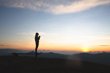 Silhouette of young  human hands  praying to god  at sunrise, Christian Religion concept background.