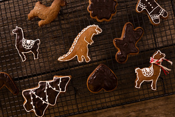 Homemade gingerbread in various shapes on an black grille on old wooden background. © Lukasz