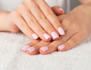 Beautiful female hand with light pink nail design..