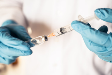 Doctor or nurse hand with nitrile glove holding flu, measles vaccine  for baby vaccination, medicine and drug concept