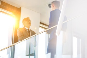Low angle view of business colleagues discussing by railing at office