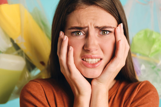 Close up irritated girl near eco bags with plastic waste scaredly looking in camera over colorful background isolated