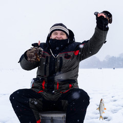 Fototapeta na wymiar Happy smiling adult fisherman showing thumbs up after successful