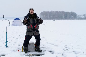Happy shouting adult fisherman after successful winter fishing a