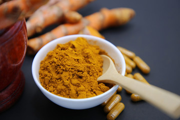 Composition with bowl of turmeric powder on white background.