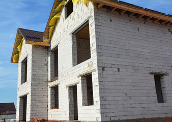 House under construction from aerated concrete blocks with metal roof and unfinished soffits.