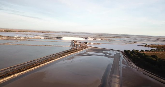vol au dessus des marais salant au coucher de soleil avec tas de sels (camels)  au loin avec eau et chemins de terre entre les diff&eacute;rents &eacute;tangs