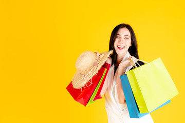 A young girl is carrying colorful shopping bags.