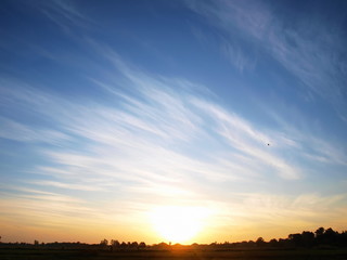 The golden sun in the morning On the background, the silhouette of the scenery and on the blue sky with beautiful white clouds
