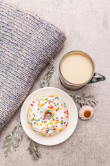 Hot coffee with a donut. Winter drink for a good mood with sweater, leaves and flowers. Old wood plank background