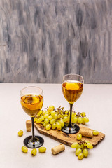 Wine glasses, fresh grapes and corks on wooden chopping board. Wine bar, winery, wine tasting...