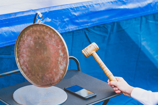 Man strike a gong with wooden hammer during a boxing match, close up