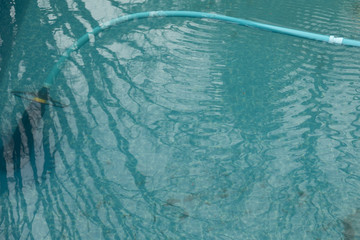 Hose in a pool that makes waves on the surface of the water