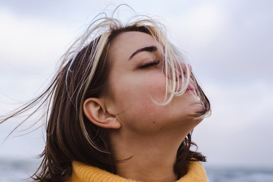 portrait of beautiful young woman in yellow pullover sweater on the beach