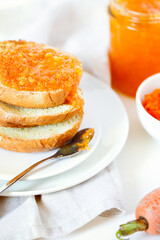 Vegetarian organic sweet carrot jam or marmalade toast topping for breakfast close-up.Healthy vegetable dessert on white background.Vertical orientation