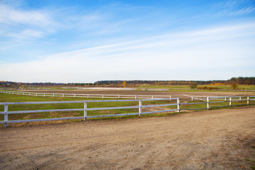 Wooden white fence on a green field. Beautiful blue sky.