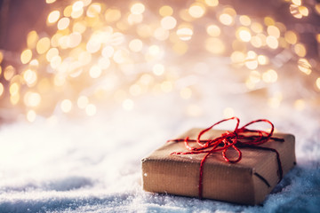 Christmas gift on snow, wrapped in eco paper.