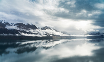 Fototapeta na wymiar Sky and mountains reflect in Lake Wakatipu near Queenstown. Moody New Zealand. Landschaft in Neuseeland