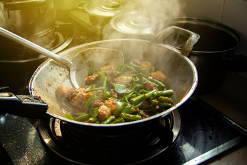Thai food menu stir fried long bean with streaky pork in pan on gas stove with a simple and warm home kitchen atmosphere in the morning.