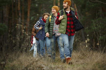 Group of friends on a camping or hiking trip in autumn day. Men and women with touristic backpacks...