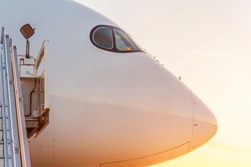 Side view close up on the nose of a passenger plane at sunset.