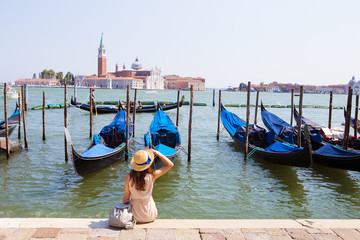 Beautiful sunny Venice-girl sitting on the pier, near the gondola
