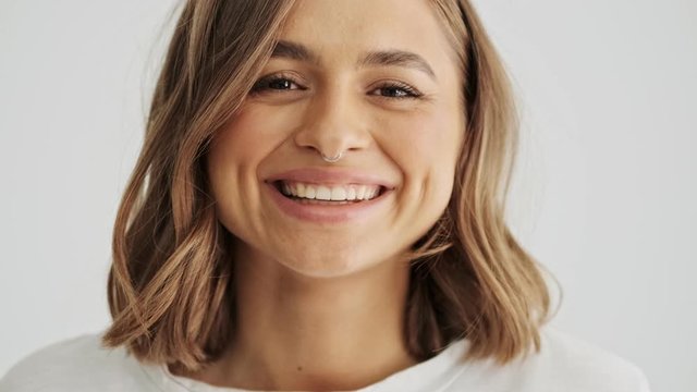 Close up view of beautiful laughing young woman wearing basic t-shirt with nose piercing isolated over white background