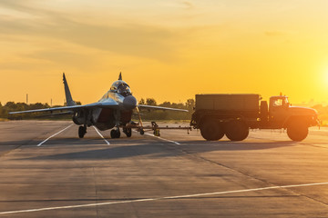 Military fighter is being pushed to a parking lot by a military vehicle at an air base in the...