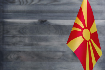 Fragment of the flag of the Republic of North Macedonia in the foreground blurred wooden background...