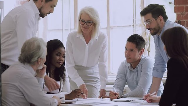 Diverse business team and old woman leader brainstorm on paperwork