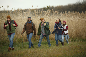 Group of friends on a camping or hiking trip in autumn day. Men and women with touristic backpacks...