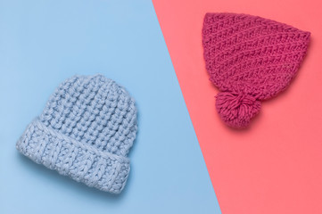 Flat lay fashionable blue and pink knitted winter hat for women on blue pink background top view. Stylish woolen hat, concept of winter accessories for the cold. Advertising, shopping, winter sale