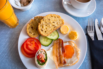 Tasty breakfast on the plate. Fried egg with bacon, bread, butter and salad.