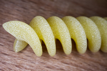 Dry italian pasta fusilli on wooden table. Macro image