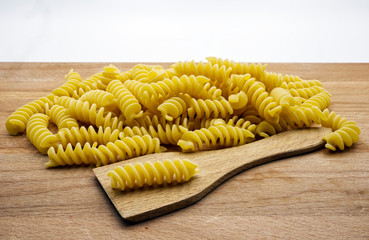 Dry italian pasta fusilli on wooden table. Macro image