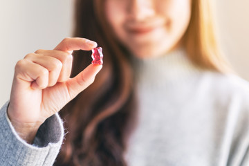 Closeup image of a beautiful woman holding and looking at a red gummy bear
