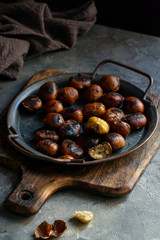 baked chestnuts, fried on the grey dark background, ready to eat, copy space